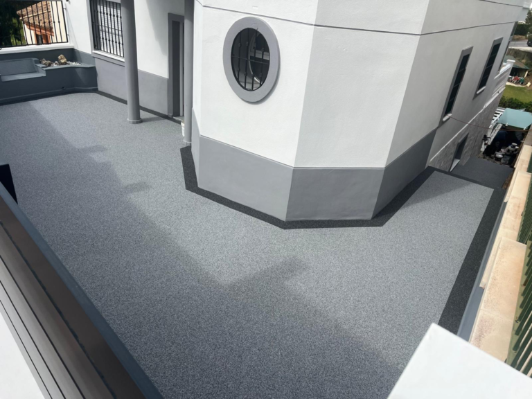 Grey stone carpet terrace wrapping around a white house with a contrasting charcoal border
