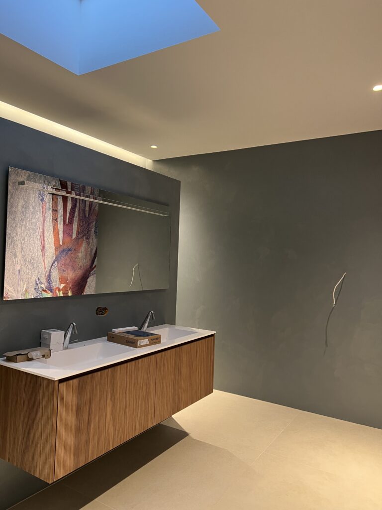 Soft grey microcement bathroom walls beside a wooden vanity