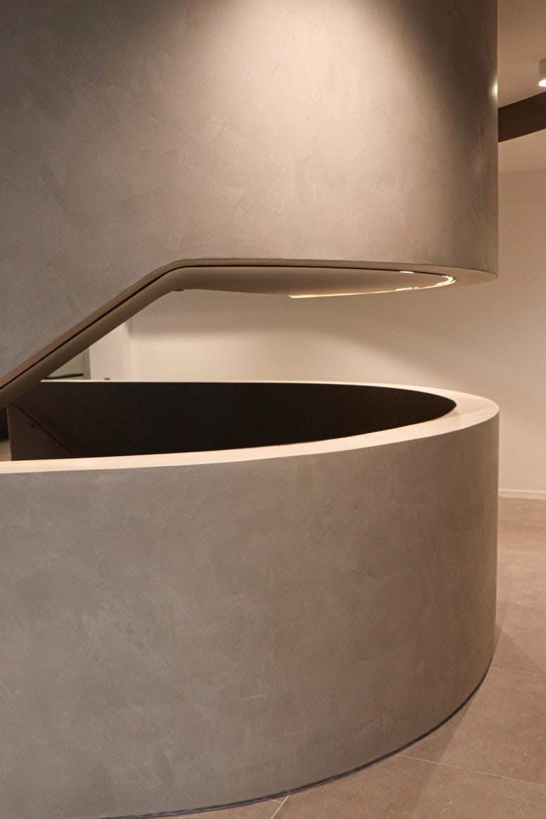 Warm beige microcement walls following a curved staircase