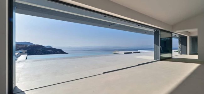 Pale continuous floor in a contemporary living area opening onto a sea-view terrace