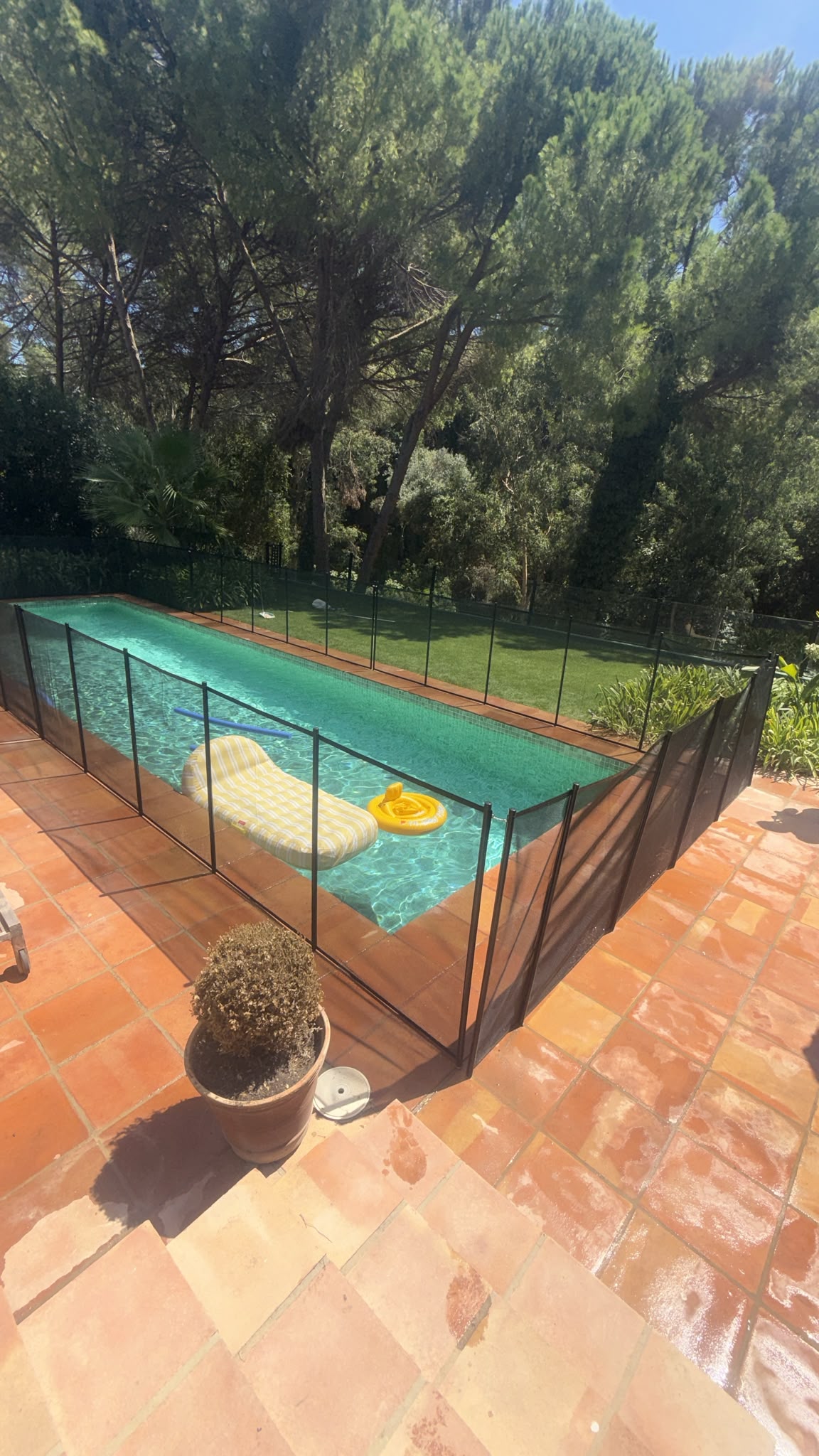 Black mesh safety fence installed around a swimming pool